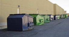 Blue And Green Skip Bins Outside Along Commercial Building